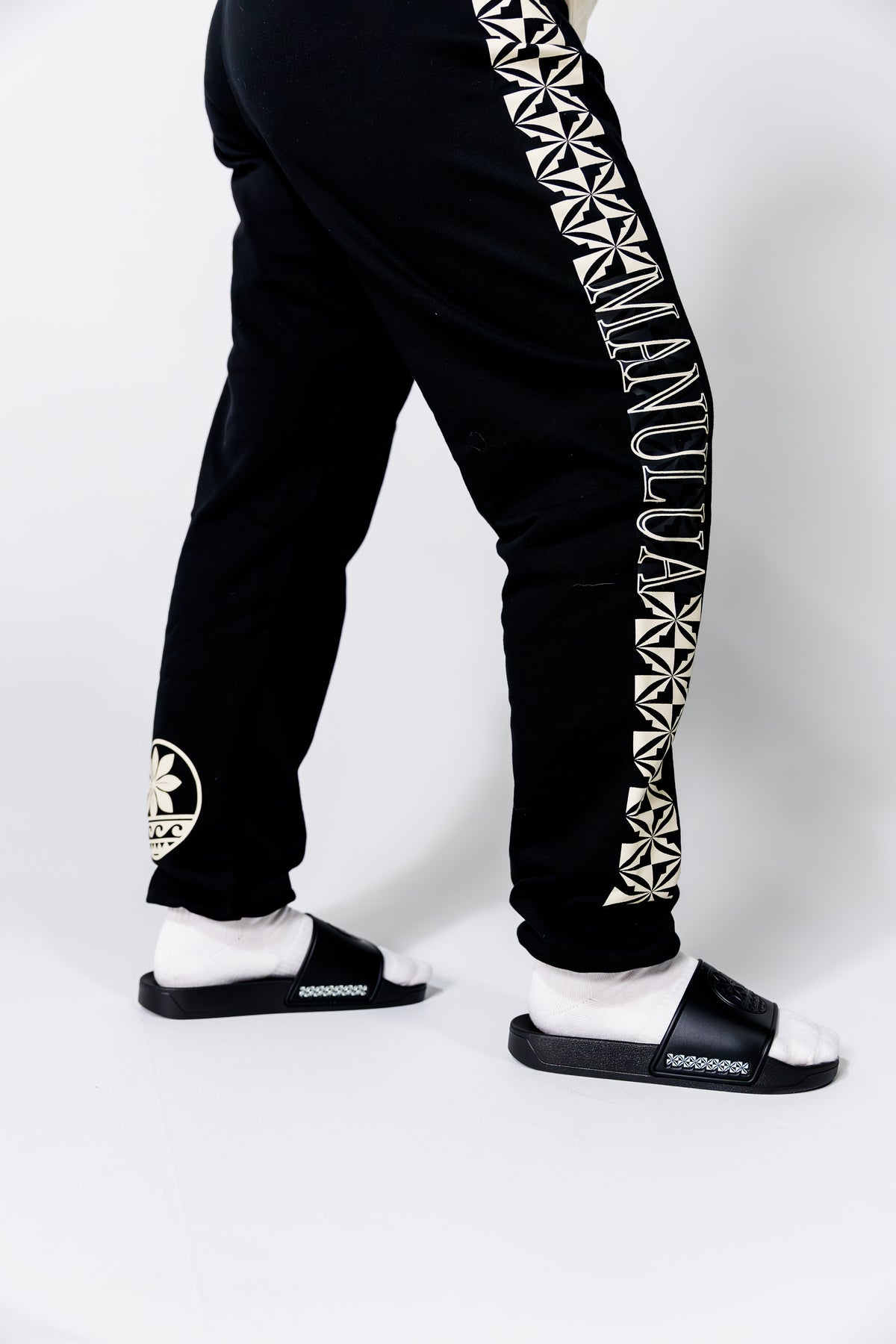 Black jogger pants with white geometric patterns and text on a white background