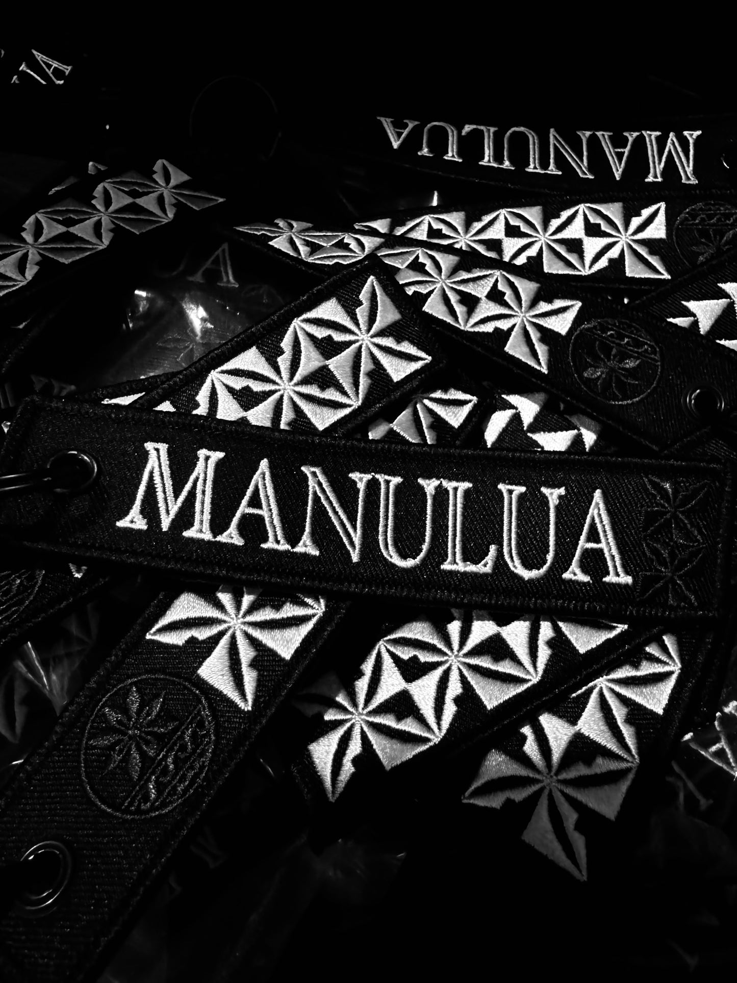 Manulua brand patches with geometric designs on a black background
