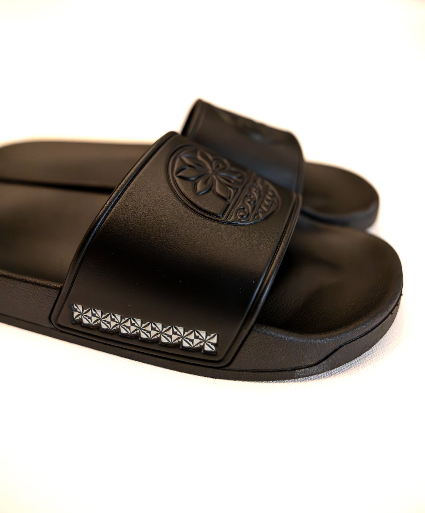 Black slide sandals with a brand logo on a white background