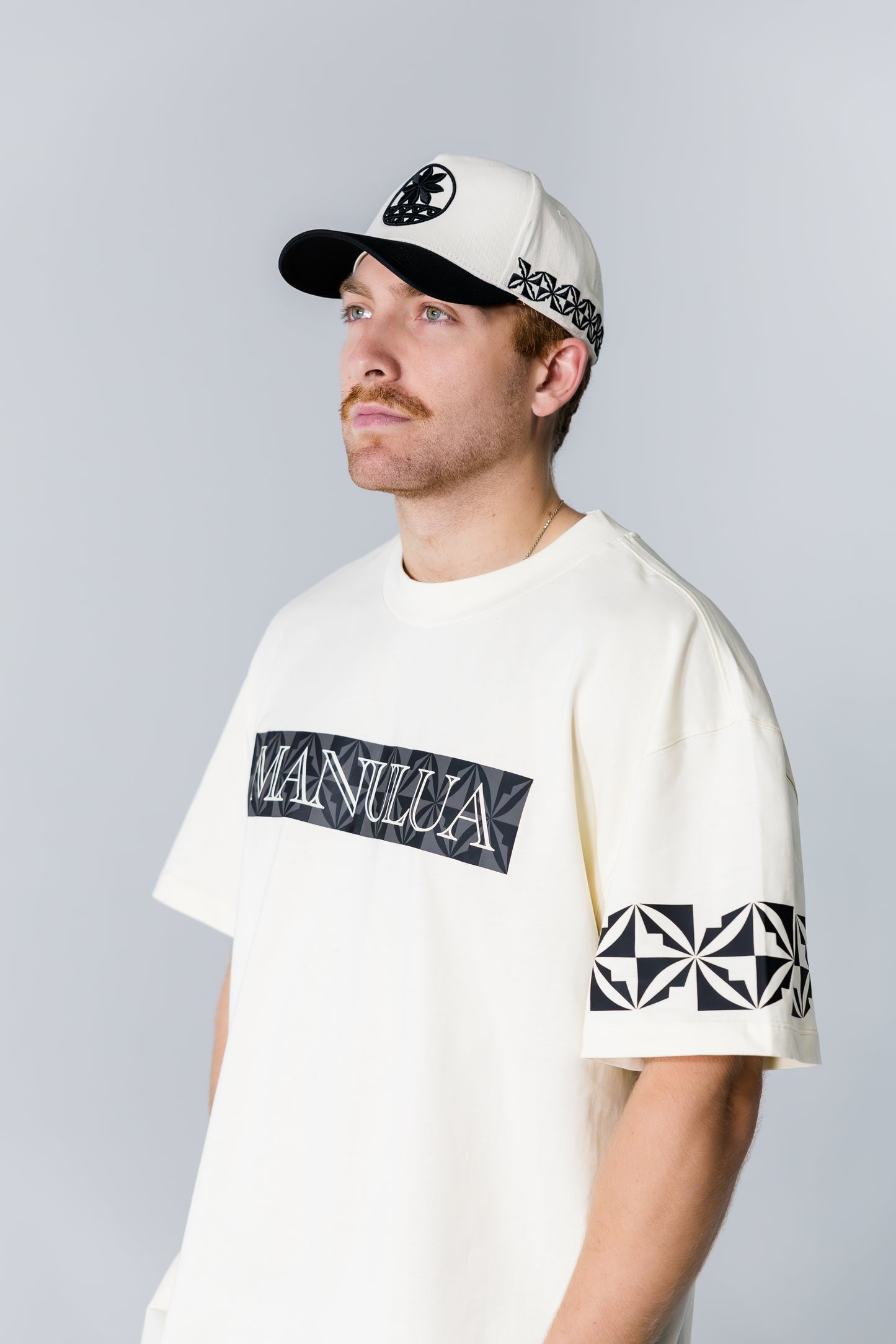 Man wearing a white t-shirt with black graphics and text, standing against a plain background