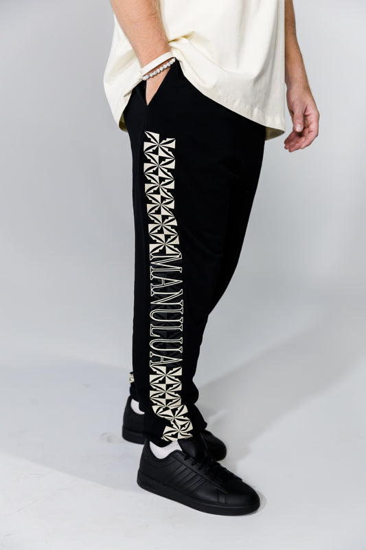 Black pants with white geometric patterns and text on a plain background