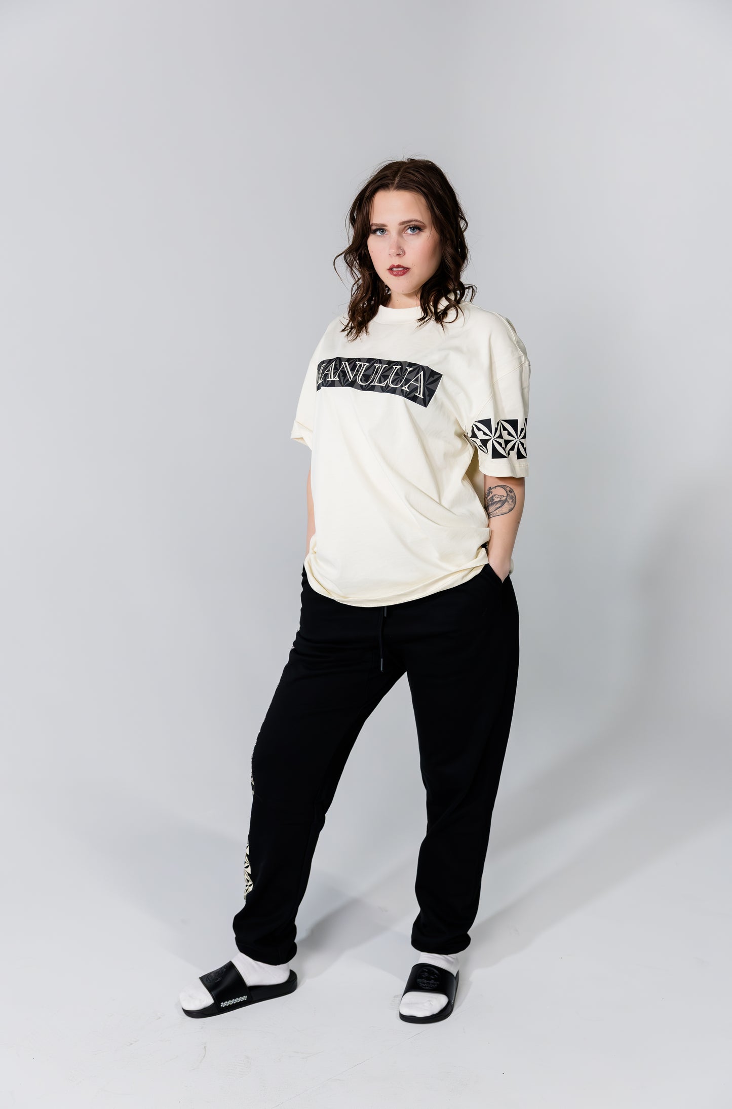 Person wearing a white sweatshirt with text and black pants on a plain background