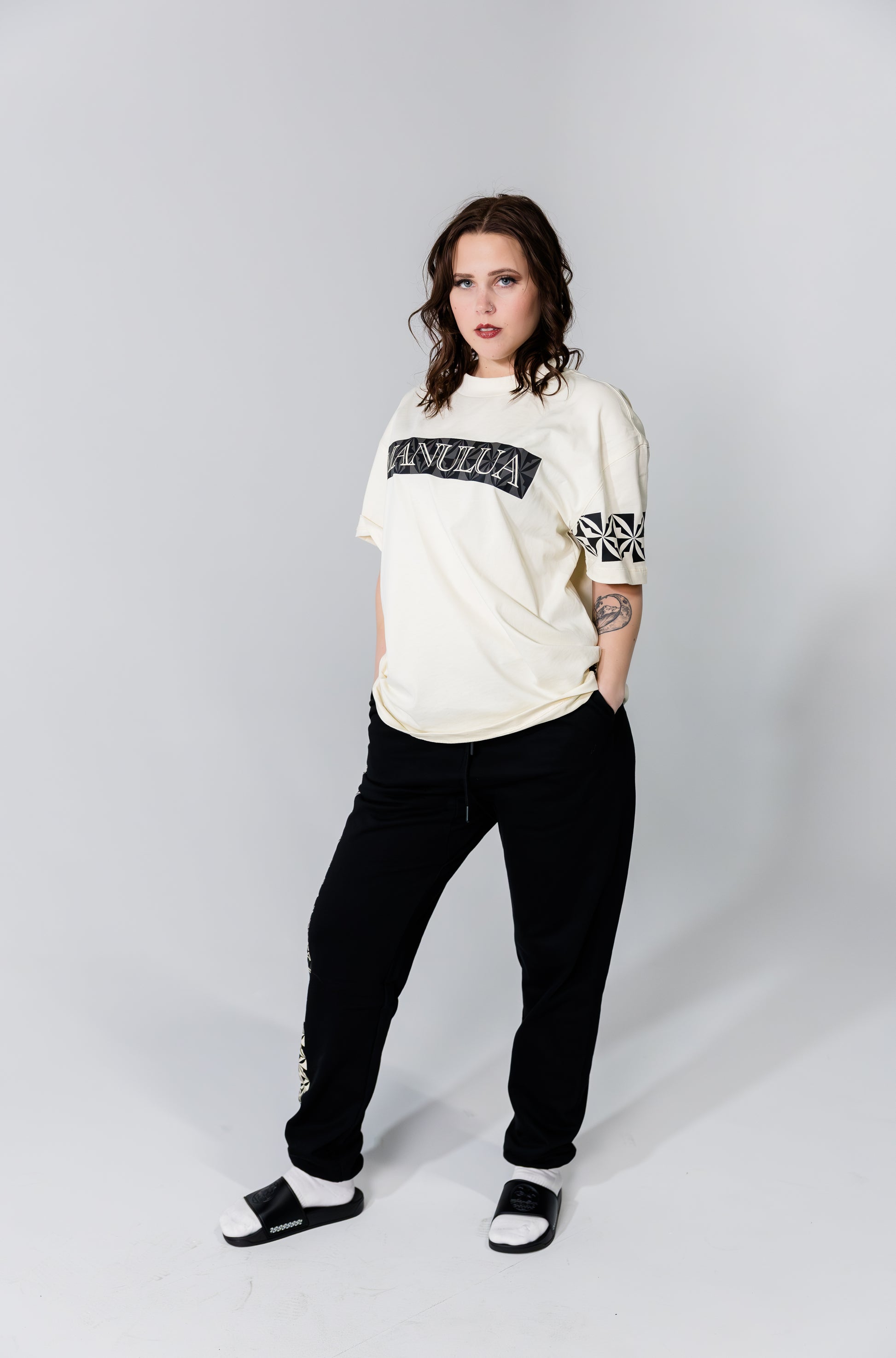 Person wearing a white sweatshirt with text and black pants on a plain background