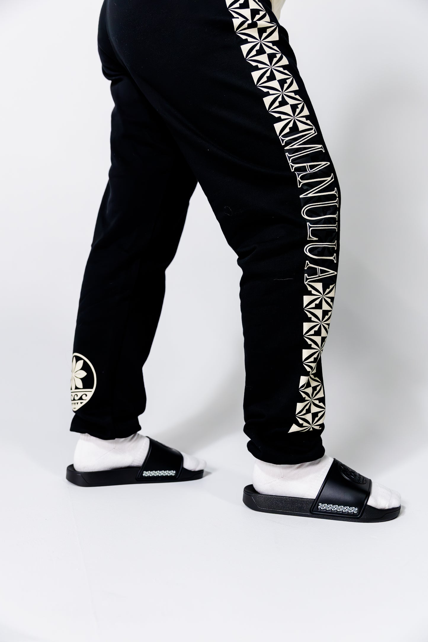 Black jogger pants with white geometric patterns and text on a white background