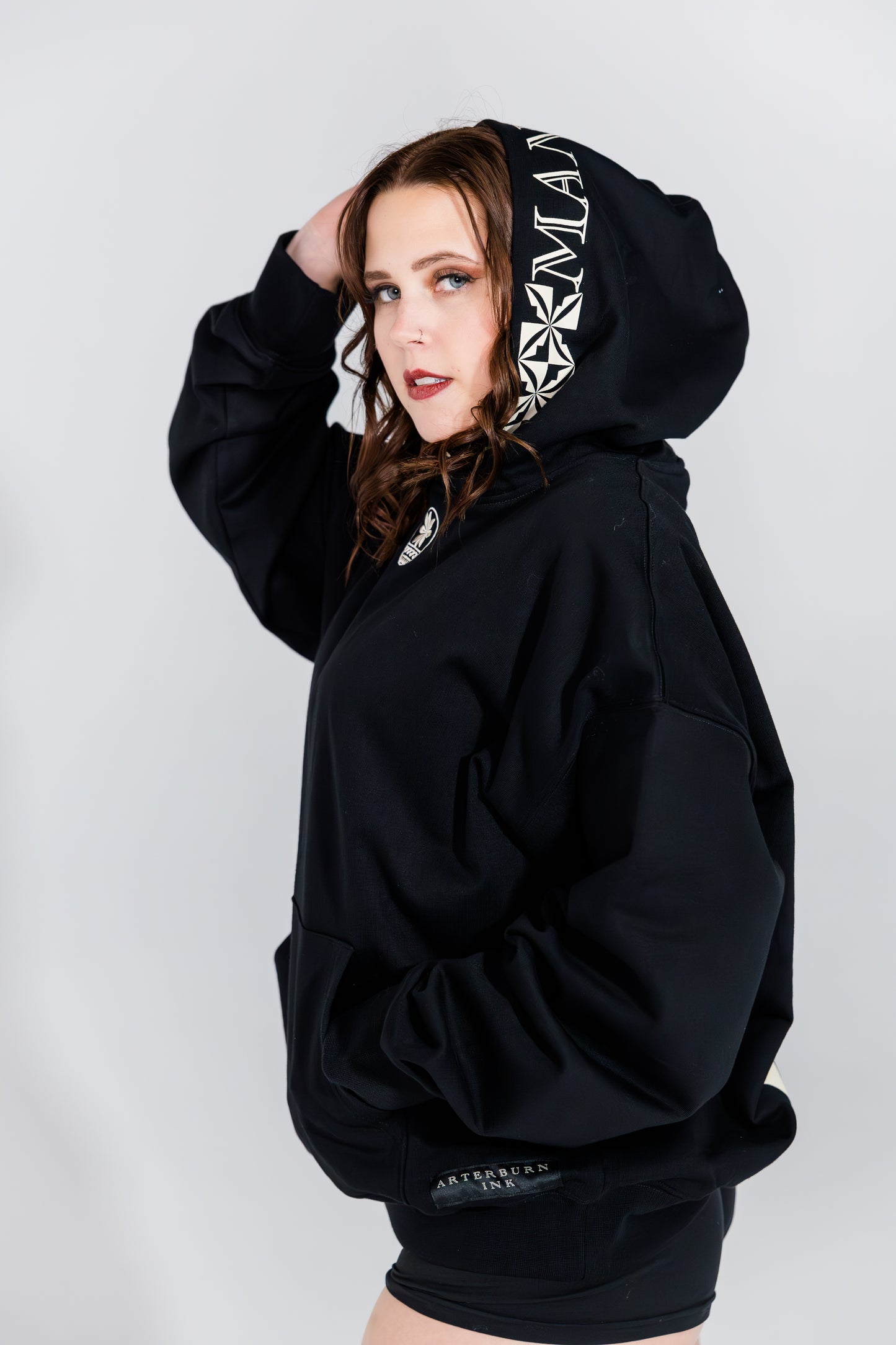 Person wearing a black hoodie with brand logo on a white background