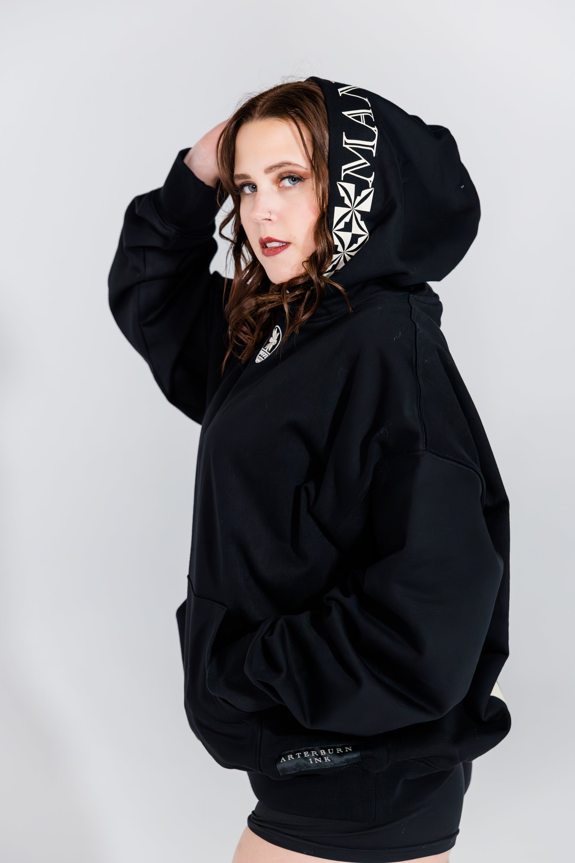 Person wearing a black hoodie with brand logo on a white background