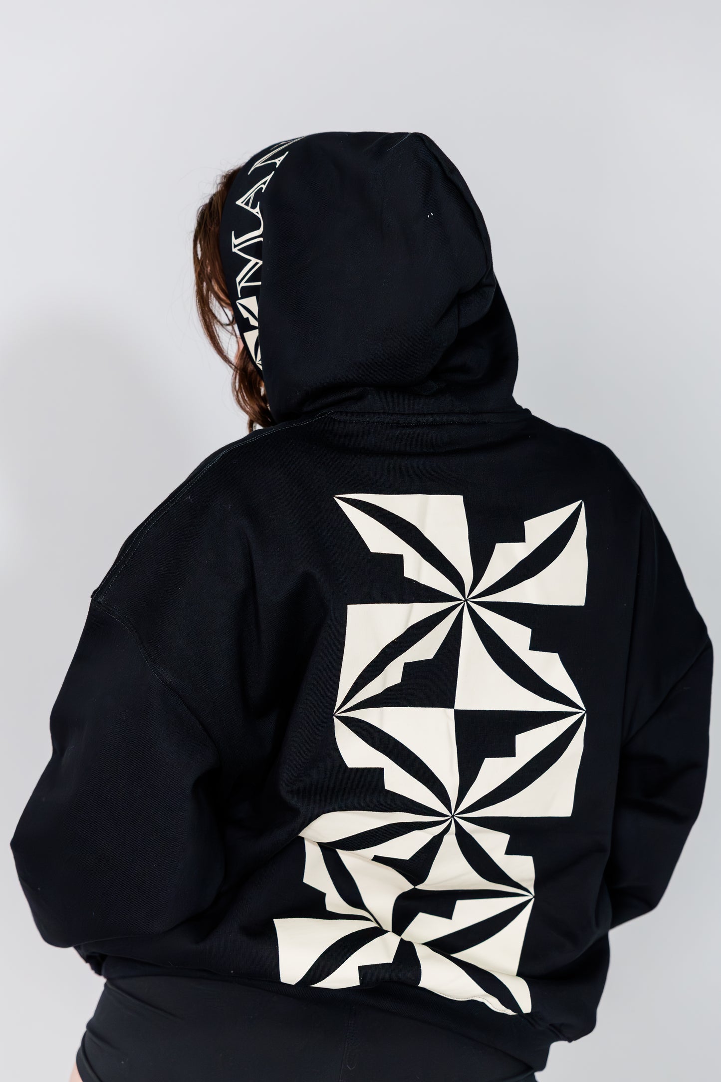 Black hoodie with geometric white patterns on a plain background