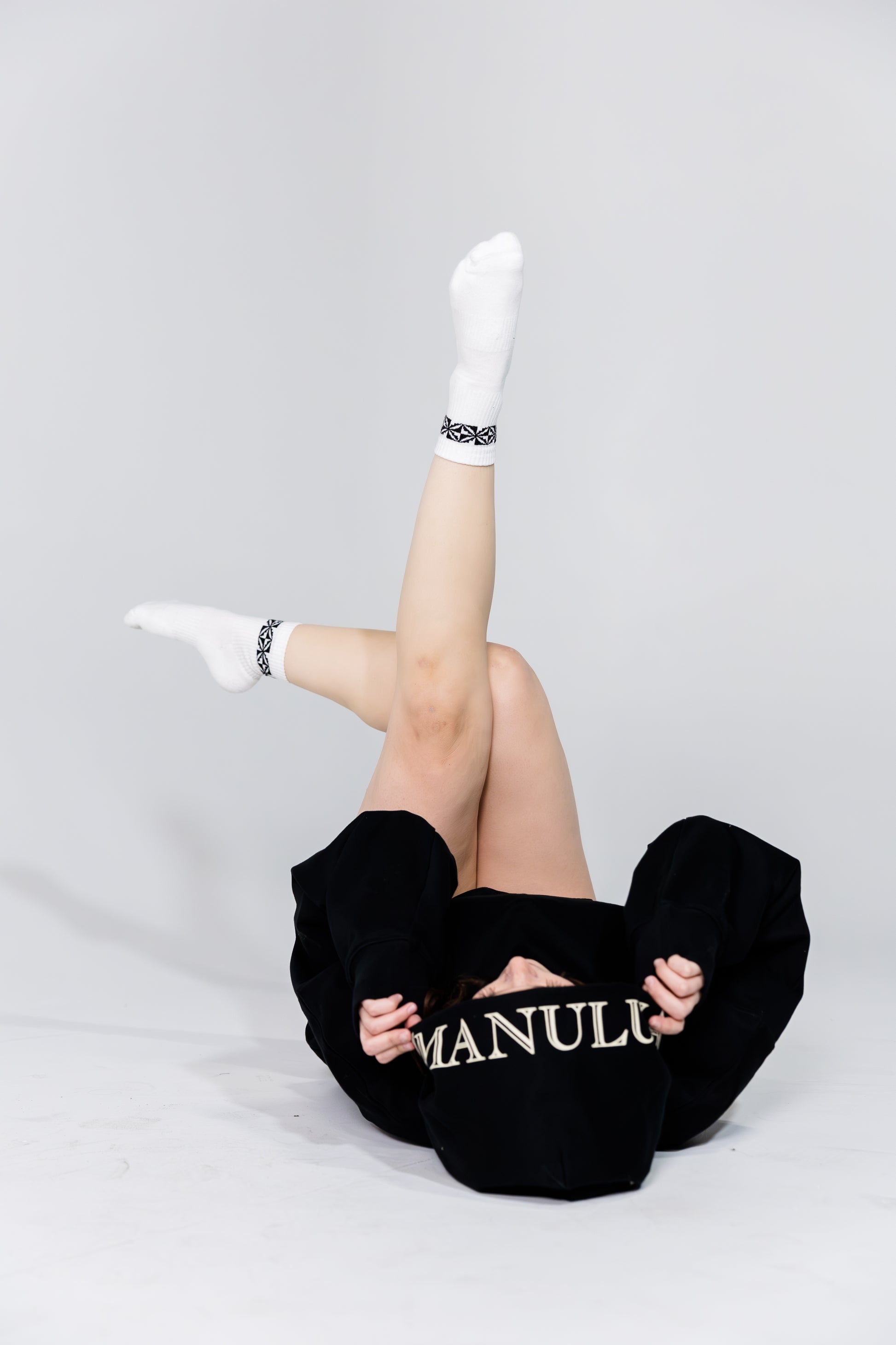 Person wearing black pants with 'Manulu' branding on a white background